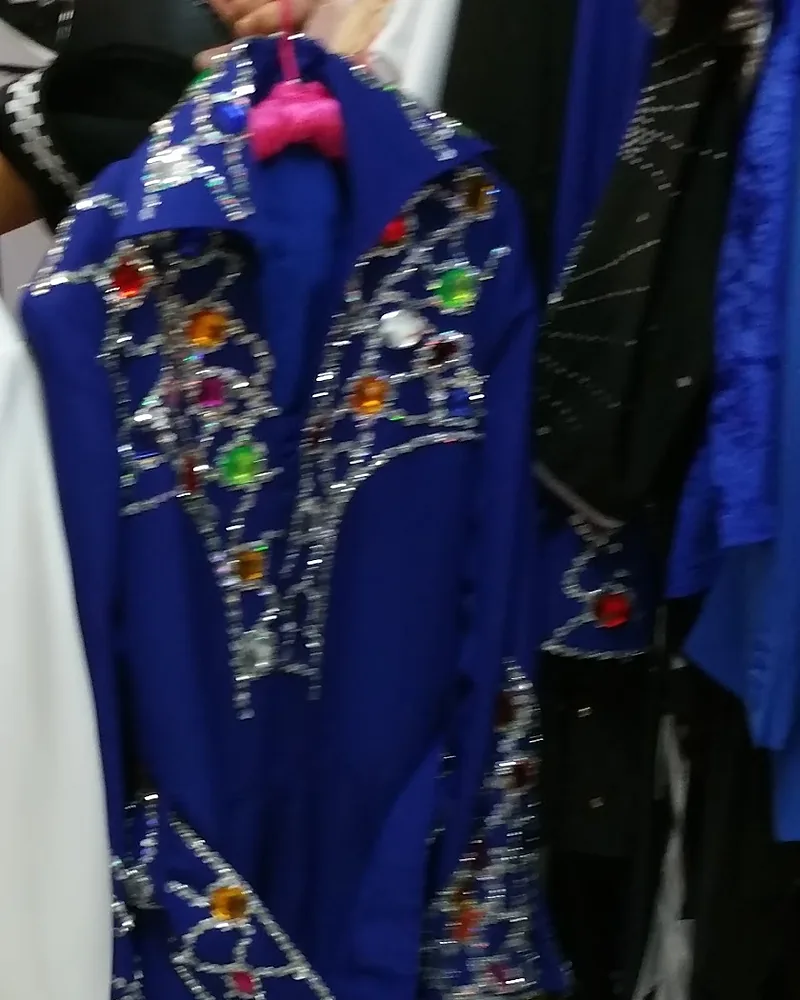 Royal blue jumpsuit covered in silver sequins and coloured jewels, hanging on the rack