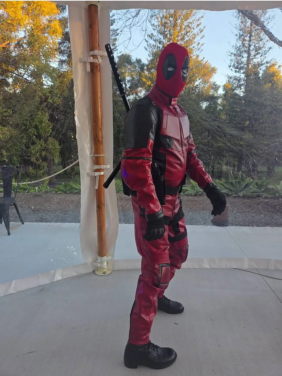 Full-suit masked character in red and black, standing on a terrace