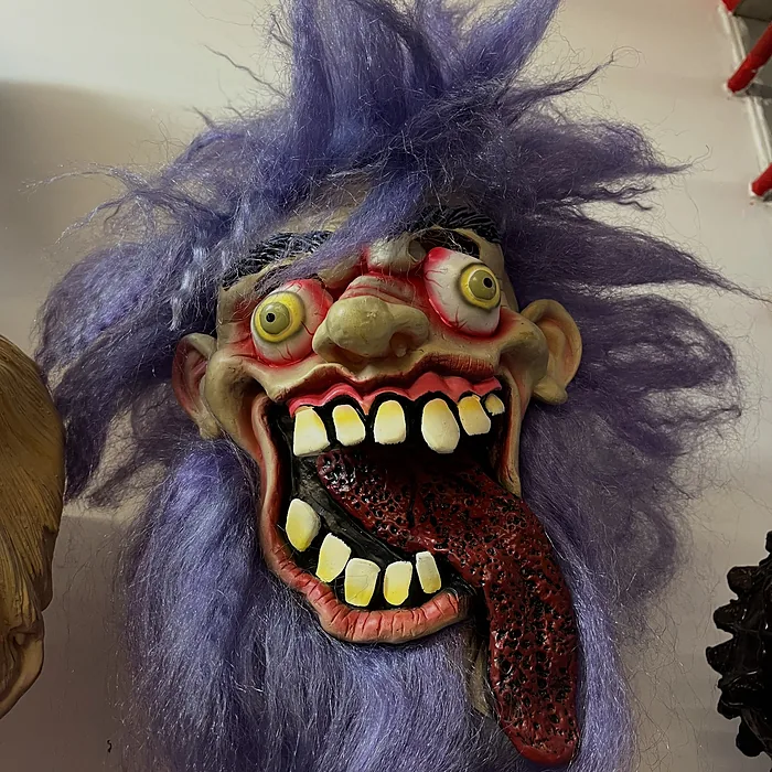 Wild-haired purple monster mask with goggle eyes and a lolling tongue