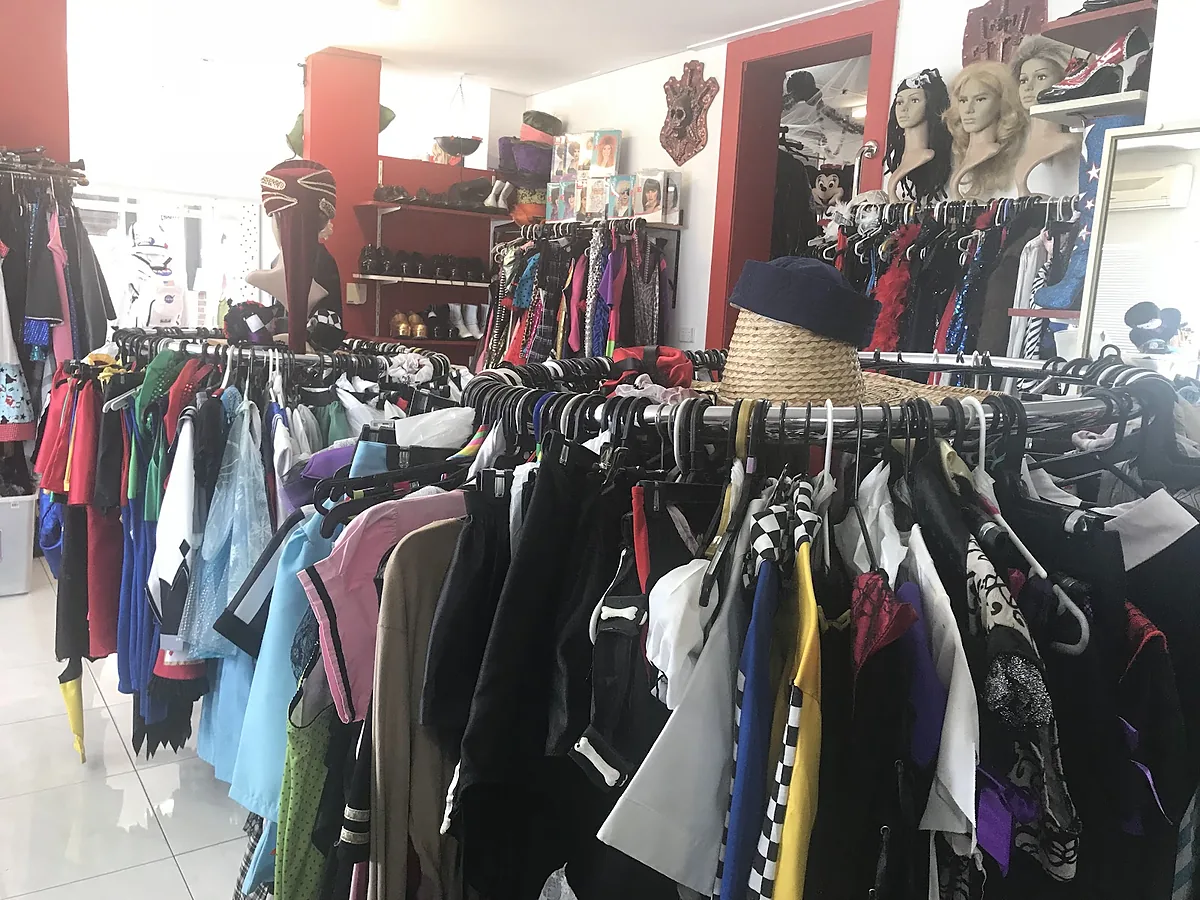 Round costume racks in the showroom with wigs, hats and shoes on the shelves behind