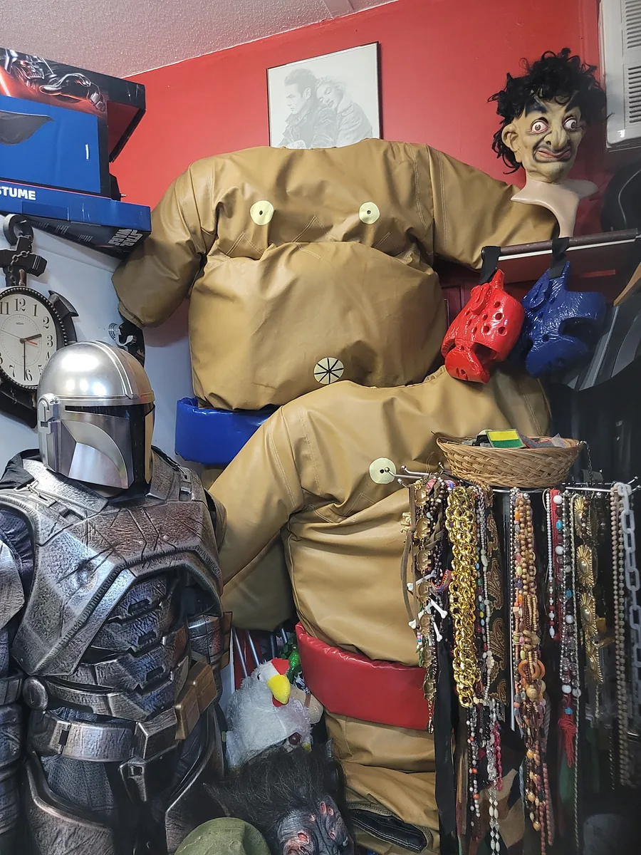 Shop corner with inflatable sumo suits, a silver armoured mannequin and racks of beads and chains